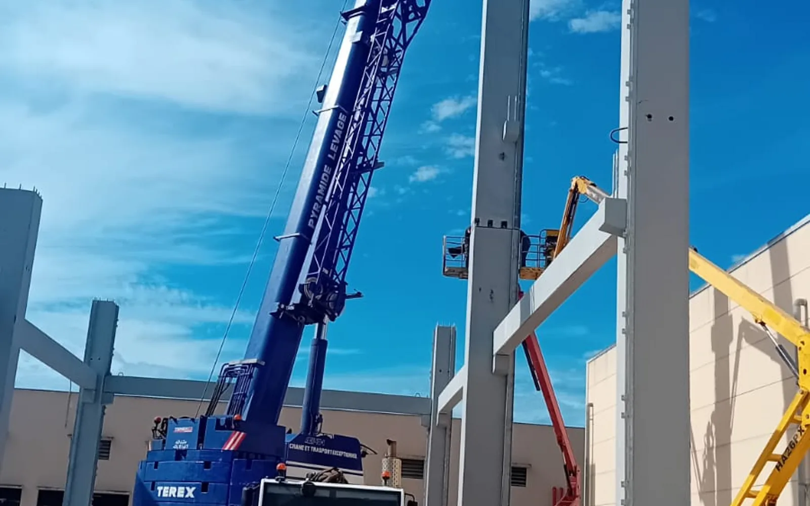 Grue mobile EasyMat levant un voile préfabriqué, équipe au sol en EPI
